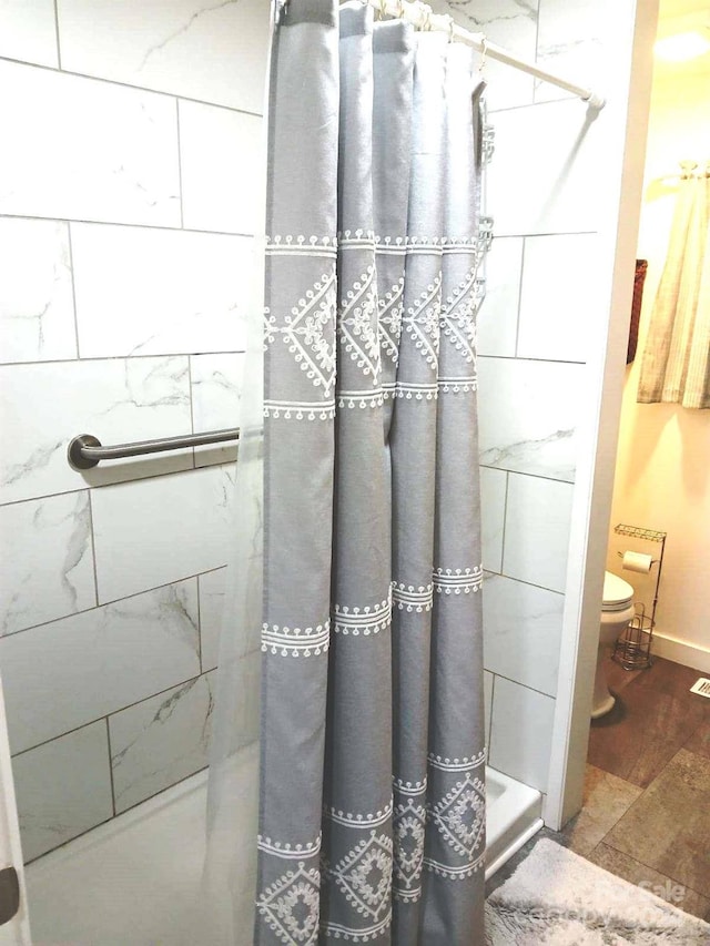 bathroom with hardwood / wood-style flooring, curtained shower, and toilet