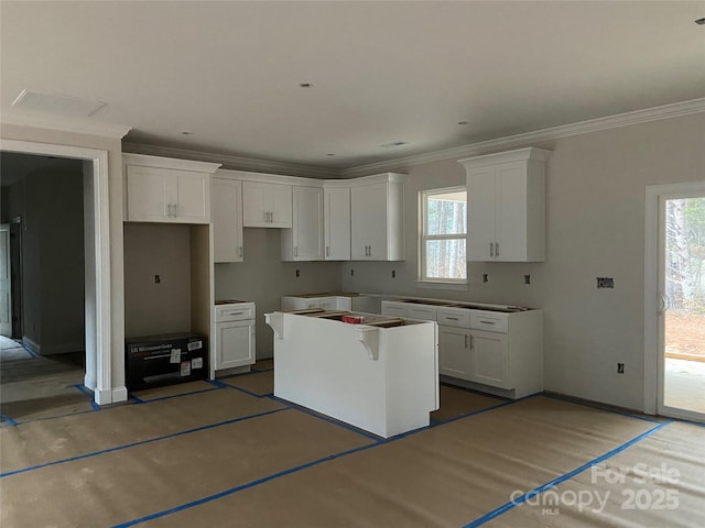 kitchen with a kitchen island, crown molding, and white cabinetry