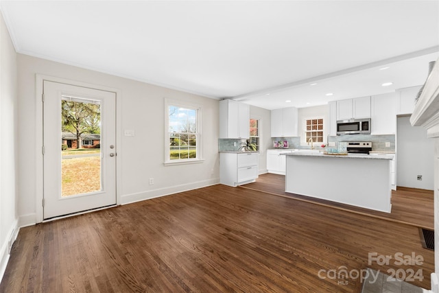 kitchen with decorative backsplash, white cabinets, dark hardwood / wood-style flooring, stainless steel appliances, and a center island