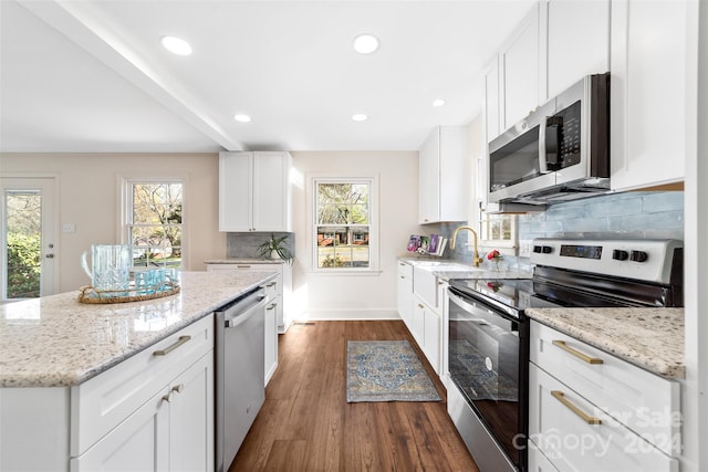 kitchen with light stone countertops, white cabinetry, dark hardwood / wood-style floors, and stainless steel appliances