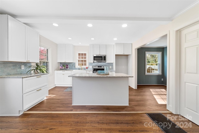 kitchen with appliances with stainless steel finishes, plenty of natural light, white cabinetry, and a center island