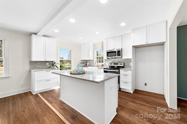 kitchen with white cabinets, appliances with stainless steel finishes, dark wood-type flooring, and a center island