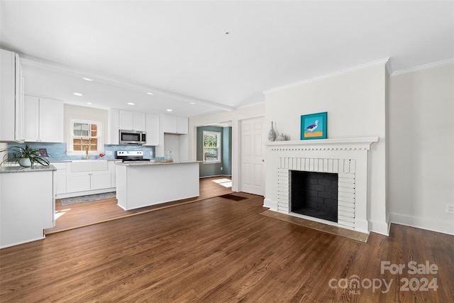 kitchen featuring dark hardwood / wood-style floors, white cabinetry, a fireplace, a kitchen island, and appliances with stainless steel finishes