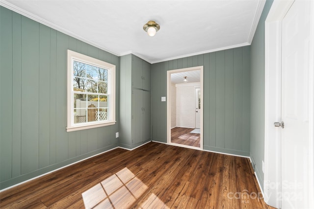 unfurnished bedroom featuring ornamental molding, wood walls, and dark hardwood / wood-style floors