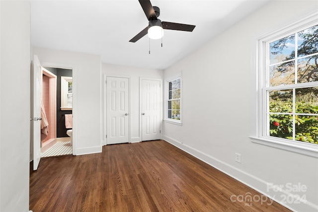 unfurnished bedroom featuring multiple closets, multiple windows, ceiling fan, and dark hardwood / wood-style flooring