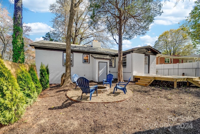 rear view of house featuring a wooden deck and an outdoor fire pit