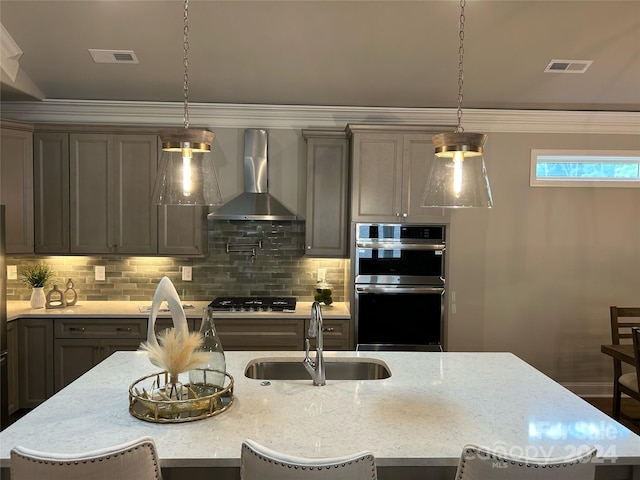 kitchen featuring wall chimney exhaust hood, sink, a breakfast bar area, and appliances with stainless steel finishes