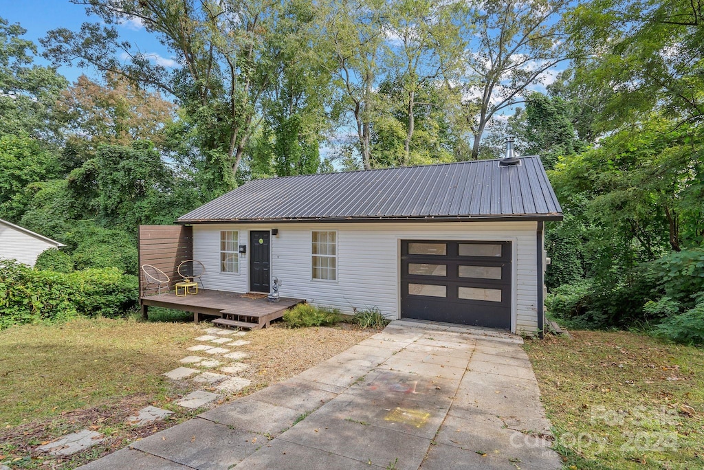 view of front of property with a deck, a garage, and a front lawn