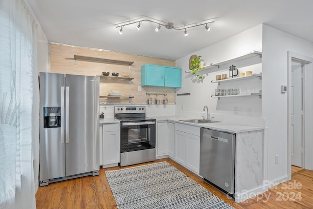 kitchen with blue cabinets, sink, white cabinetry, stainless steel appliances, and light wood-type flooring