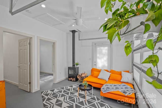 interior space featuring ceiling fan, concrete flooring, and a wood stove