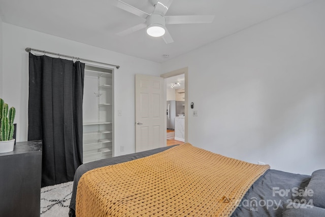 bedroom with stainless steel fridge with ice dispenser, ceiling fan, and a closet