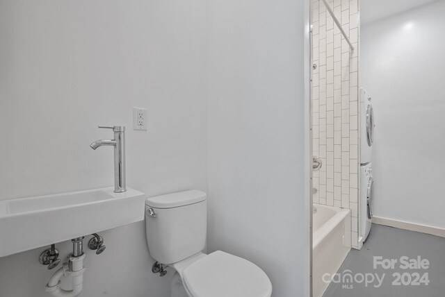 full bathroom featuring sink, toilet, tiled shower / bath combo, and stacked washer and clothes dryer