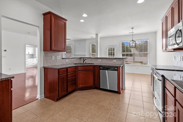 kitchen with sink, hanging light fixtures, light hardwood / wood-style floors, kitchen peninsula, and stainless steel appliances