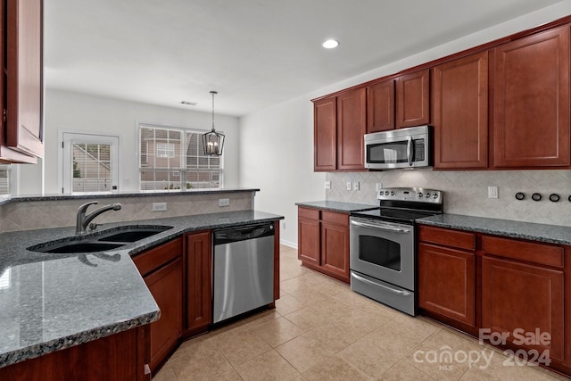 kitchen with decorative backsplash, appliances with stainless steel finishes, dark stone counters, sink, and hanging light fixtures