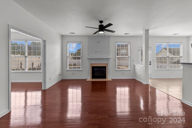 unfurnished living room featuring plenty of natural light, dark wood-type flooring, and ceiling fan