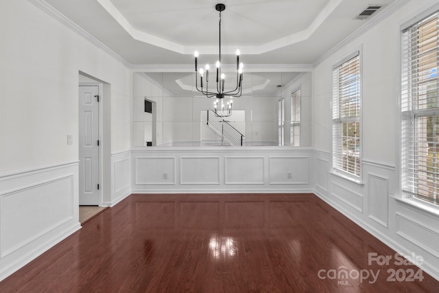 unfurnished dining area featuring ornamental molding, dark wood-type flooring, and a raised ceiling