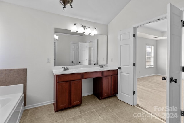 bathroom with vanity, a tub, lofted ceiling, and tile patterned floors