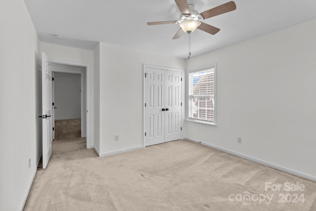 unfurnished bedroom featuring a closet, ceiling fan, and light carpet