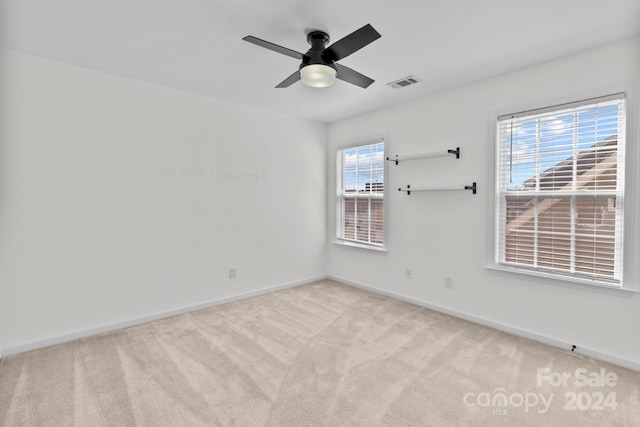 carpeted spare room featuring ceiling fan and a healthy amount of sunlight