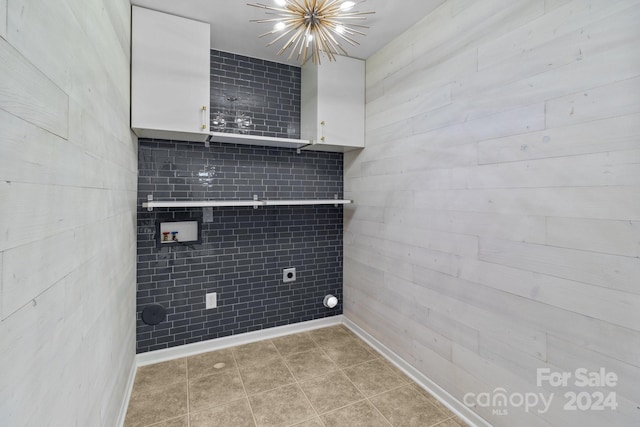 washroom featuring light tile patterned flooring, hookup for a washing machine, electric dryer hookup, cabinets, and an inviting chandelier