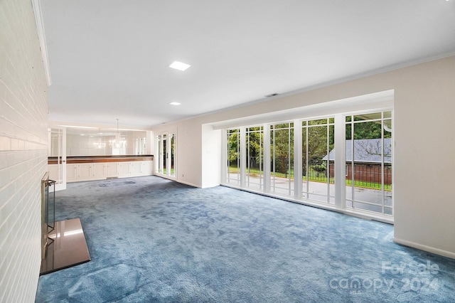 unfurnished living room with a chandelier, dark colored carpet, and crown molding