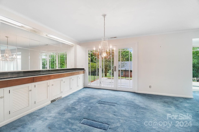 unfurnished dining area featuring carpet floors, crown molding, and an inviting chandelier