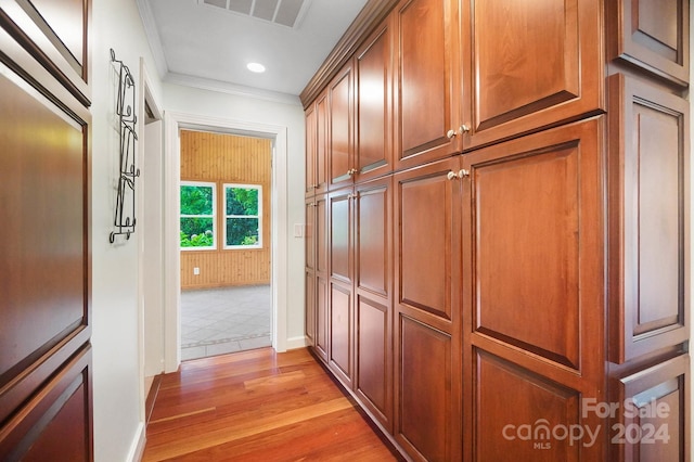 corridor with light hardwood / wood-style flooring and ornamental molding