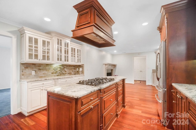 kitchen with a kitchen island, appliances with stainless steel finishes, light wood-type flooring, and decorative backsplash