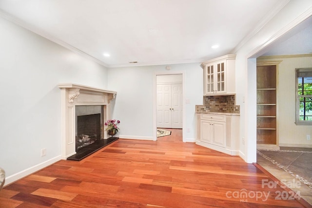 unfurnished living room featuring light wood-type flooring, ornamental molding, and a tiled fireplace