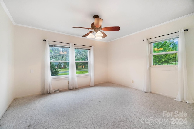 carpeted spare room featuring ornamental molding, ceiling fan, and plenty of natural light