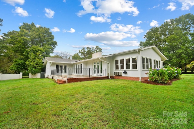 rear view of property with a lawn and a deck