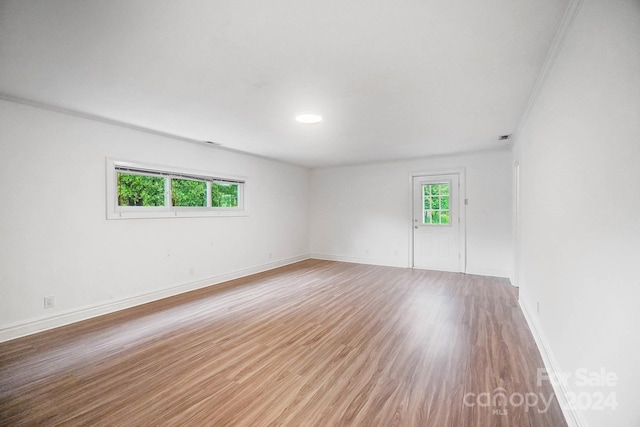 empty room featuring a healthy amount of sunlight, ornamental molding, and hardwood / wood-style flooring