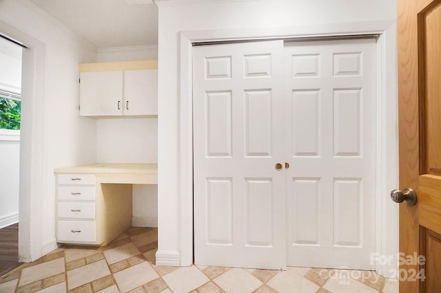 interior space with built in desk and ornamental molding