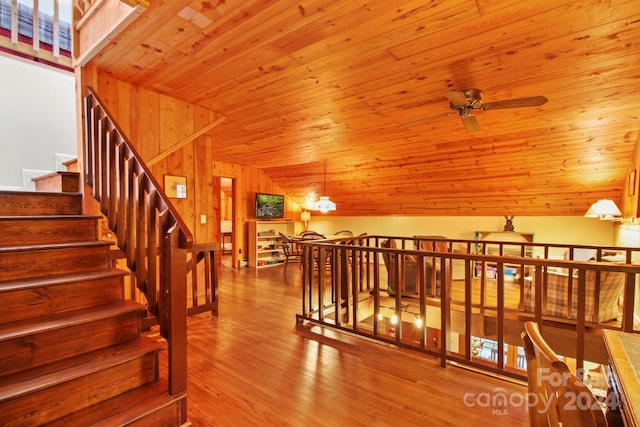 stairs with hardwood / wood-style floors, ceiling fan with notable chandelier, lofted ceiling with skylight, and wooden ceiling