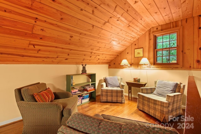 sitting room featuring light hardwood / wood-style flooring, vaulted ceiling, wooden walls, and wood ceiling