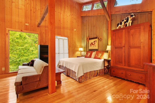 bedroom featuring light wood-type flooring, a skylight, high vaulted ceiling, and multiple windows