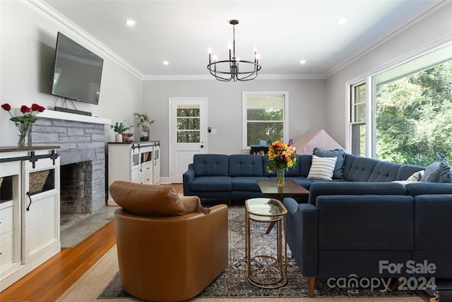 living room featuring hardwood / wood-style flooring, a fireplace, crown molding, and a notable chandelier