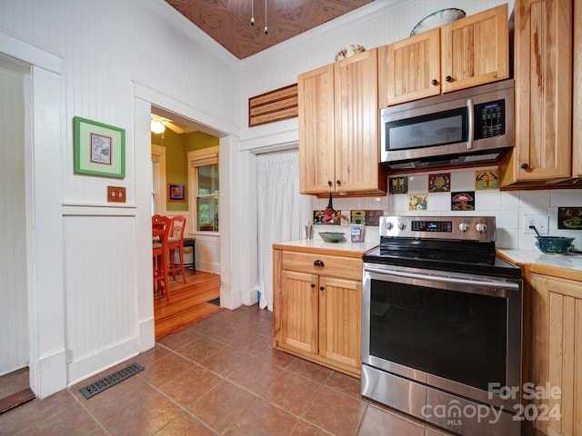 kitchen featuring light brown cabinets, ornamental molding, stainless steel appliances, tile patterned floors, and decorative backsplash