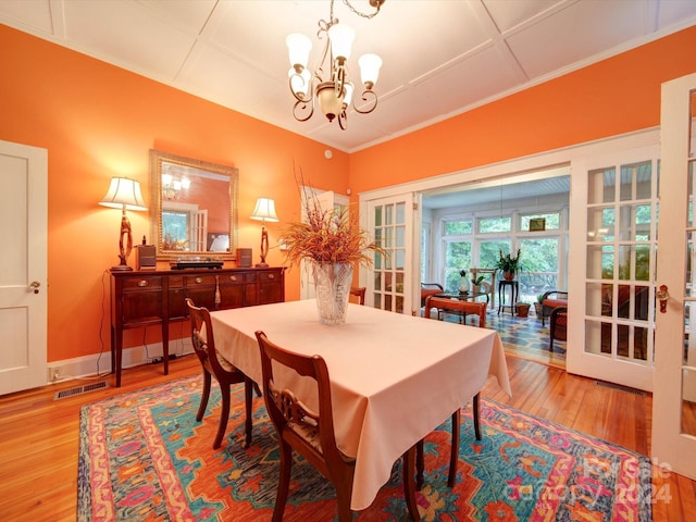 dining area with a notable chandelier, light wood-type flooring, and french doors