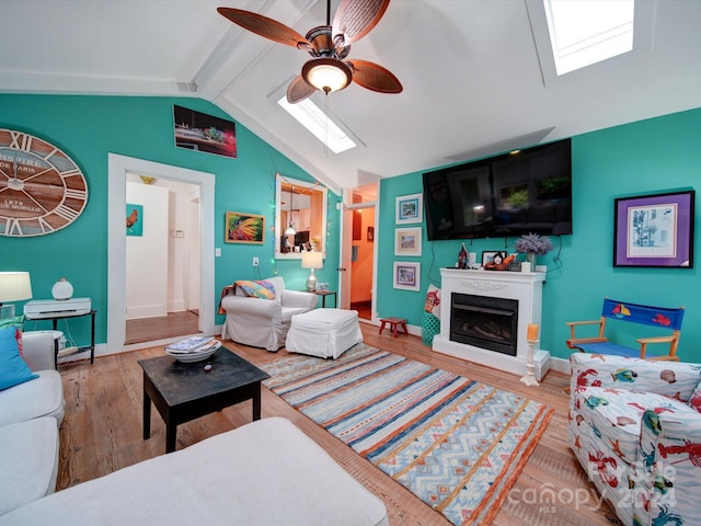 living room with lofted ceiling with skylight, hardwood / wood-style floors, and ceiling fan