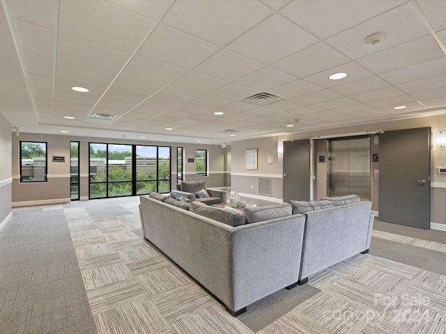 living room with a paneled ceiling, light colored carpet, and elevator