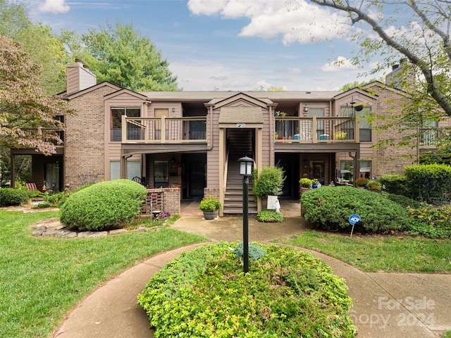 view of front of house featuring a balcony and a front lawn