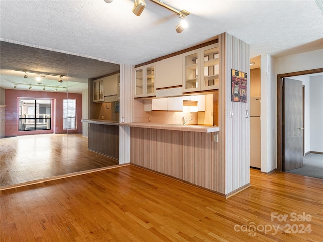 kitchen with a breakfast bar area, a textured ceiling, light wood-type flooring, and hanging light fixtures