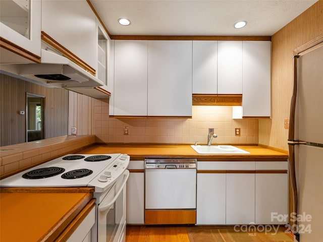 kitchen featuring light wood-type flooring, sink, white cabinets, decorative backsplash, and white appliances