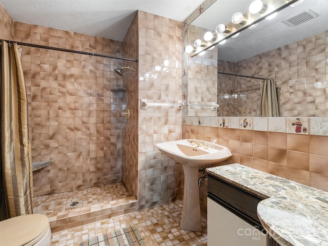 bathroom featuring tile walls, tile patterned flooring, a textured ceiling, walk in shower, and toilet