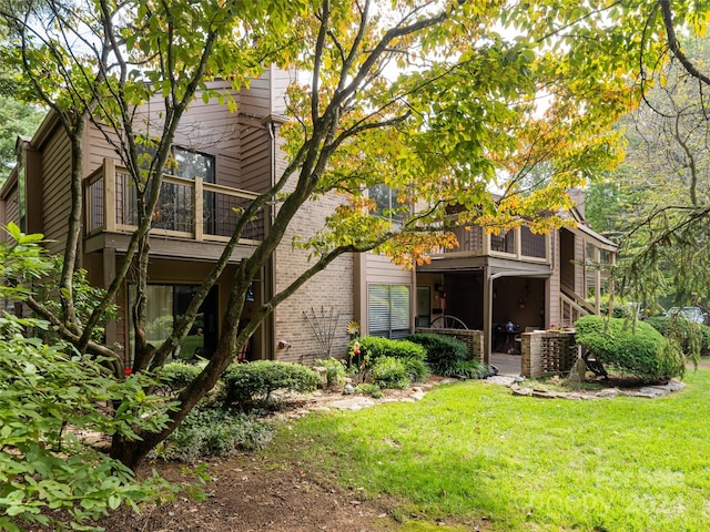 back of property featuring central AC unit, a balcony, and a lawn