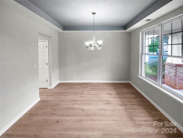 unfurnished dining area featuring light wood-type flooring, an inviting chandelier, and plenty of natural light