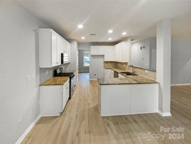 kitchen featuring appliances with stainless steel finishes, kitchen peninsula, dark stone countertops, and sink