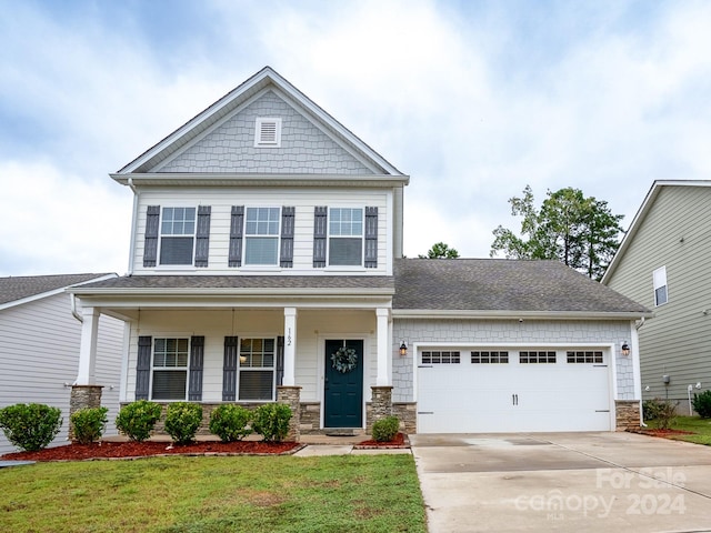 craftsman-style home with a garage, a front lawn, and covered porch