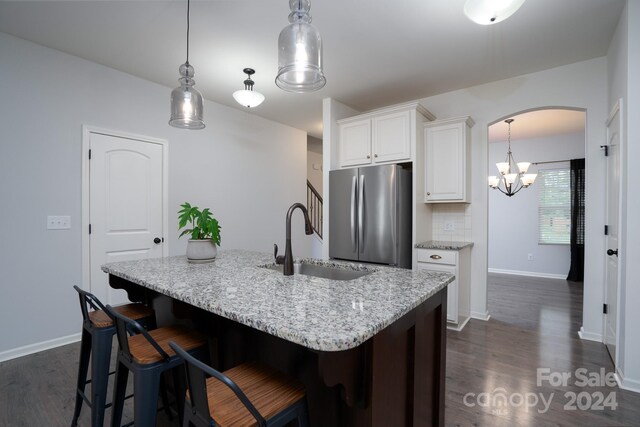 kitchen featuring white cabinetry, sink, a kitchen island with sink, and stainless steel fridge